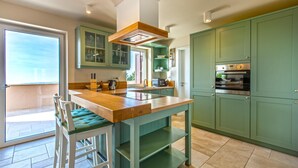 A modern kitchen with a wooden island, green cabinets, and a built-in oven. - Luksuzna Vila Gradin z bazenom (Gracisce)