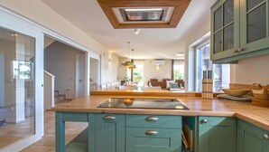 A modern kitchen with a central island, teal cabinetry, and a skylight above. - Luksuzna Vila Gradin z bazenom (Gracisce)