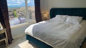 A bedroom with a bed, a nightstand, a lamp, and a window with curtains.