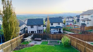 A residential backyard with a grassy lawn, a hammock, and a garden area.