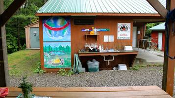 A rustic cabin with a mural of a globe and forest scene, a sink, and a small outdoor seating area.