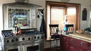 A kitchen with a Viking stove, a decorative backsplash, a clock, and a chef's hat on a chair. - The Center of Vancouver, Spacious Elegant Interior, Spectacular Outdoor Living (Vancouver)