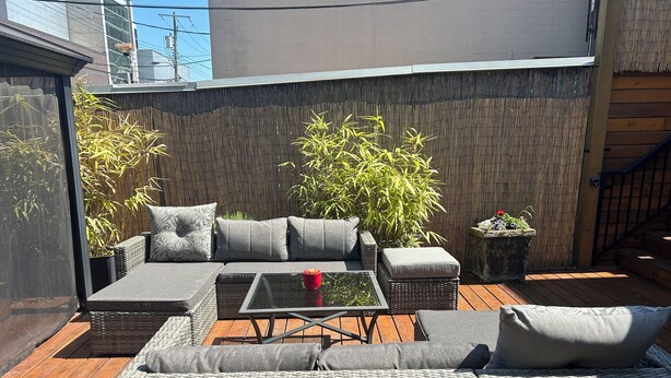 A patio with wicker furniture, a glass table, and a bamboo plant. - The Center of Vancouver, Spacious Elegant Interior, Spectacular Outdoor Living (Vancouver)