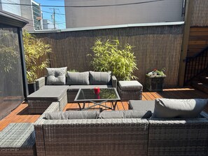 A patio with wicker furniture, a glass table, and a bamboo plant. - The Center of Vancouver, Spacious Elegant Interior, Spectacular Outdoor Living (Vancouver)