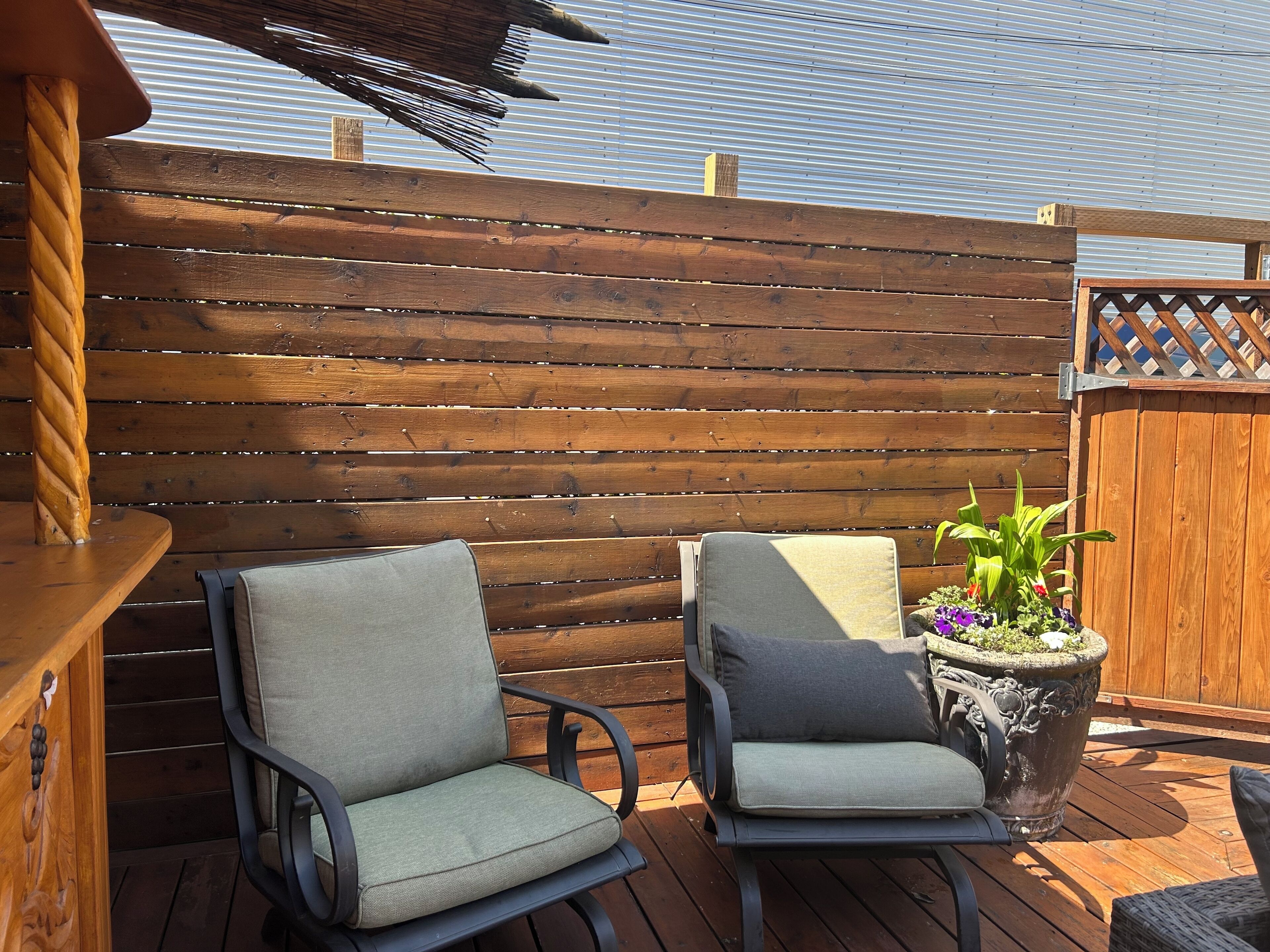 A wooden deck with two chairs and a potted plant.