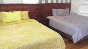 Two comfortable beds with matching pillows, a wooden headboard, and a window with white curtains.