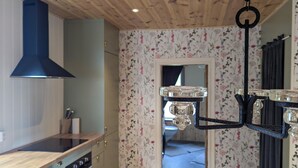 Een keuken met houten kastjes, een zwarte afzuigkap en een hangende lamp.