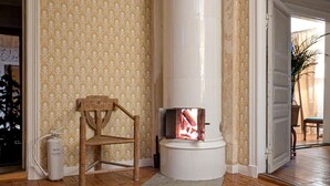 Een kamer met een witte open haard, een houten stoel en een witte verwarming.