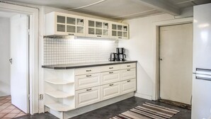 Une cuisine de taille réduite avec des meubles blancs, un pare-feu en carrelage et une machine à café posée sur le plan de travail.