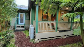 Surrounded by lush greenery, this charming home features a welcoming porch with a white railing.