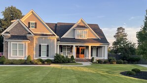 A two-story house with a brick facade, a welcoming front porch, and a well-maintained lawn. - Perfect Masters Golf Rental Home - 12 miles from the Augusta National (North Augusta)