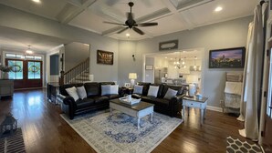 A spacious living room with a black leather sofa set, a coffee table, and a patterned rug. A ceiling fan and recessed lighting are visible. - Perfect Masters Golf Rental Home - 12 miles from the Augusta National (North Augusta)