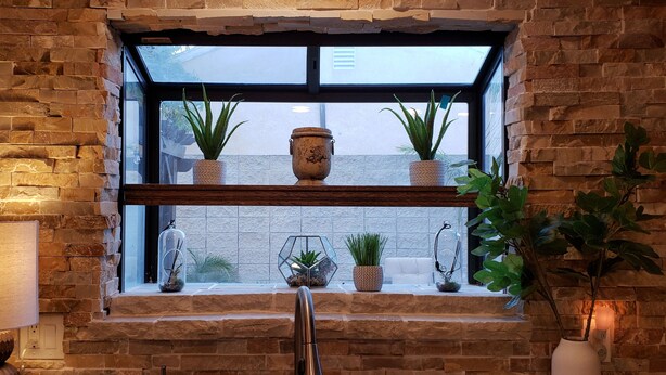 A stone-framed window with shelves holding potted plants and decorative items. - Colorful 2-bdr, 2-bth unique serenity. (Modesto)