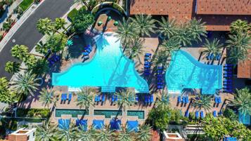 Une grande piscine avec plusieurs couloirs de nage, entourée de palmiers et de chaises longues.