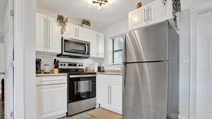 Una cucina moderna con mobili bianchi, elettrodomestici in acciaio inossidabile e pavimento in legno.