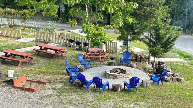 An outdoor seating area with picnic tables and blue chairs arranged around a fire pit. - DRIFTWOOD RESORT BULL SHOALS (Bull Shoals)