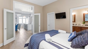 A hotel room with a bed, a TV mounted on the wall, and a bathroom visible through an open door.