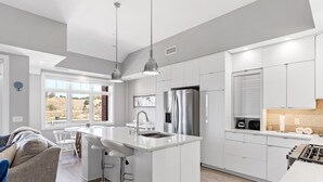 A modern kitchen with white cabinetry, stainless steel appliances, and a large island with bar stools.