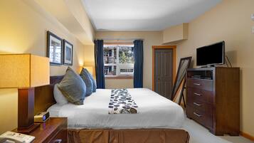 Una habitación de hotel con una cama, un escritorio con lámpara, televisión y cómoda.
