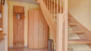Una escalera de madera que sube a un segundo piso, un armario de madera y un suelo de baldosas.
