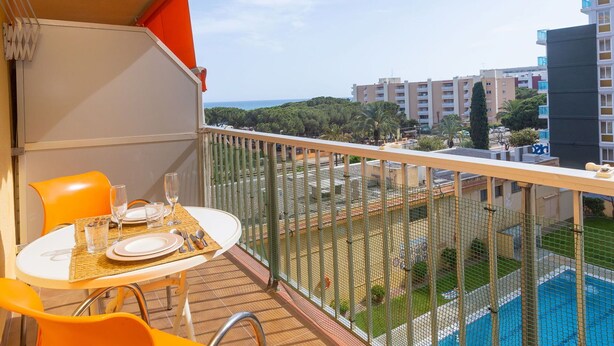 A balcony with a table set for two, overlooking a swimming pool and a cityscape. - Beautiful apartment for 4 guests with WIFI, pool, TV and balcony (Santa Susanna)