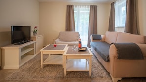 A living room with a TV, two sofas, a coffee table, and a window with curtains. - Nice apartment for 4 guests with WIFI, TV and terrace (Rijeka)