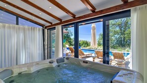 Ein Whirlpool mit Blick auf einen Swimmingpool und Sitzgelegenheiten im Freien.