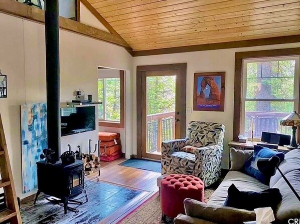 Una sala de estar acogedora con chimenea, un sillón estampado y un sofá.