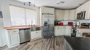 A modern kitchen with white cabinetry, stainless steel appliances, and a wooden floor.