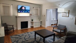 Un salon avec une cheminée, un téléviseur fixé au mur et un canapé.