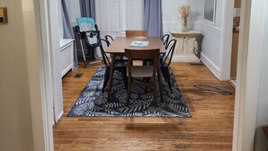 Un coin repas avec une table et des chaises en bois, un ventilateur de plafond et un tapis à motifs.