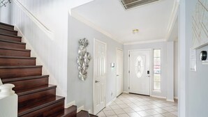 Una scala conduce a un pianerottolo con un elemento decorativo a parete, una porta bianca e un pavimento piastrellato.