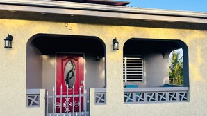 A building with a red door, number 94, and two arched windows with decorative grills. - Tropical Getaway Home (Frederiksted)