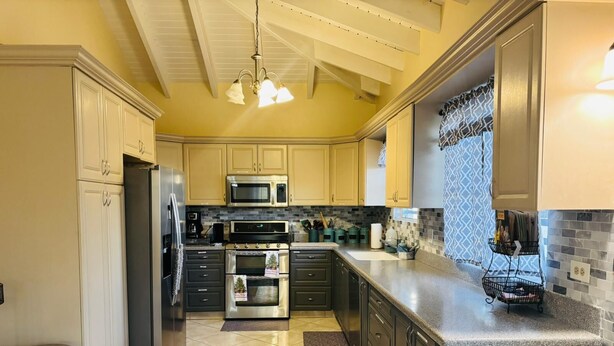 A modern kitchen with stainless steel appliances, a granite countertop, and a patterned backsplash. - Tropical Getaway Home (Frederiksted)
