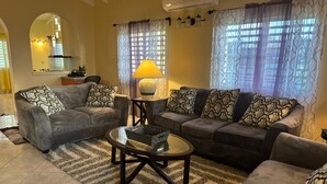 A living room with two sofas, a coffee table, and patterned cushions. - Tropical Getaway Home (Frederiksted)
