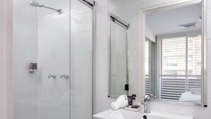 Une salle de bain moderne avec une douche à parois de verre, un lavabo blanc et un grand miroir.
