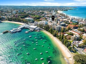 An aerial view of a coastal city with a marina, buildings, and a beach.