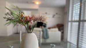 Un intérieur moderne avec un vase blanc contenant des fleurs, posé sur une table en verre.