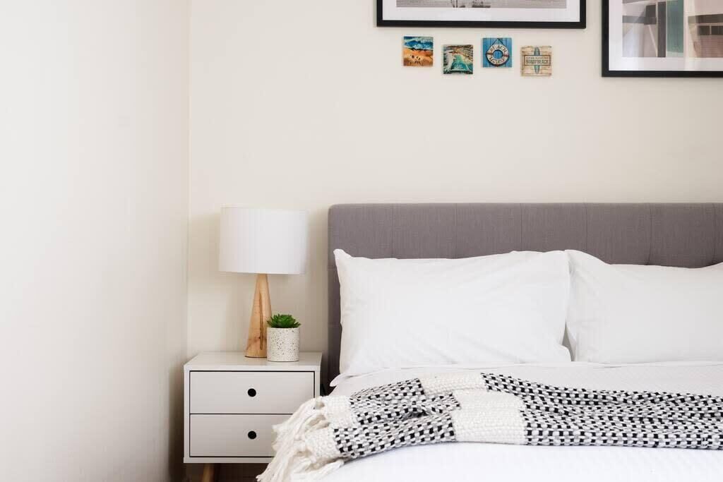 A neatly arranged bedroom with a bed, a bedside table with a lamp, and a small potted plant.