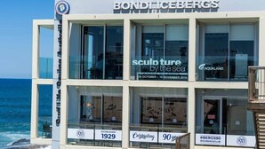 Un immeuble à plusieurs étages doté de grandes fenêtres, une enseigne indiquant « Bond Icebergs » et « sculptures au bord de la mer », et une célébration des 90 ans de l’établissement, fondé en 1929.