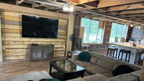 A cozy living room with a large TV, wooden walls, a sofa, and a foosball table.