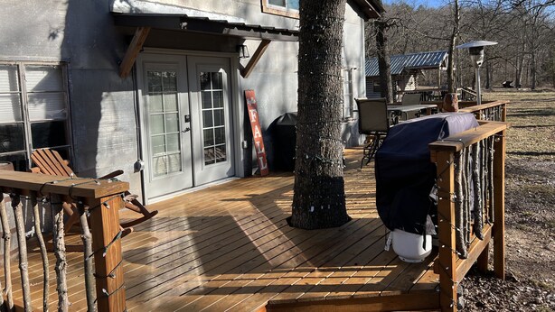A wooden deck with a covered seating area, a barbecue grill, and a 'Welcome' sign.
