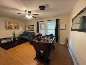 A living room with a foosball table, a ceiling fan, a sofa, and a coffee table.
