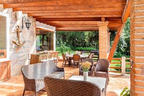 An outdoor patio with wicker furniture, a stone wall with an anchor decoration, and a brick structure.