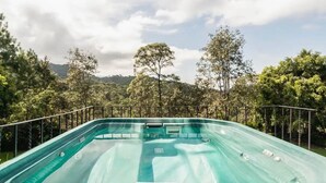Piscina com tobogã, cercada por árvores e colinas.