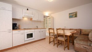 A compact kitchen with white cabinets, a built-in oven, and a dining table with chairs.