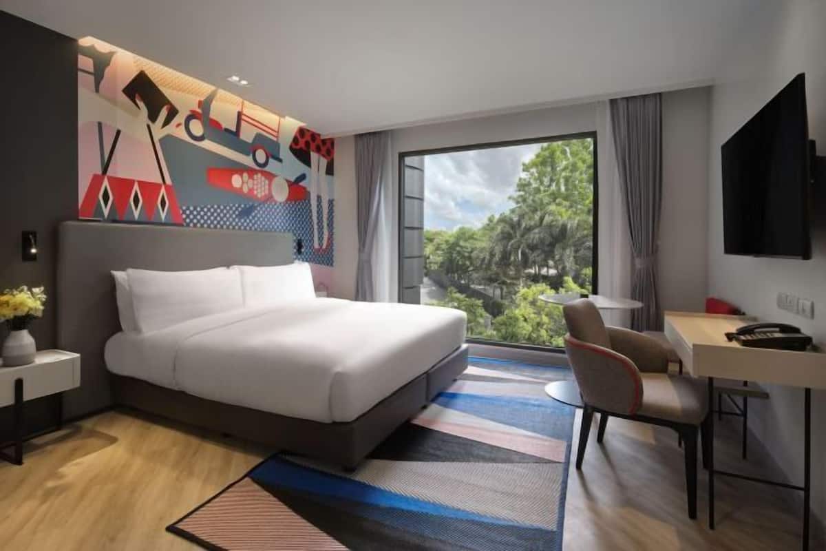 A modern hotel room with a large bed, a desk, a TV, and a view of the outdoors.