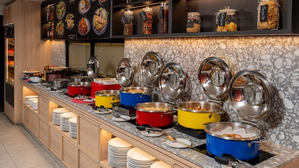 A buffet setup with multiple serving stations, each with a variety of dishes and utensils. - Oakwood Studios Sukhumvit Bangkok (Bangkok)