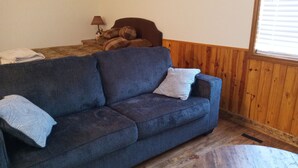 A cozy room with a blue sofa, a wooden coffee table, and a lamp on a side table.