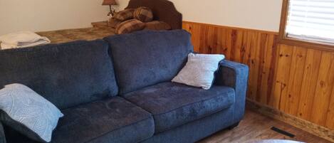 A cozy room with a blue sofa, a wooden coffee table, and a lamp on a side table.